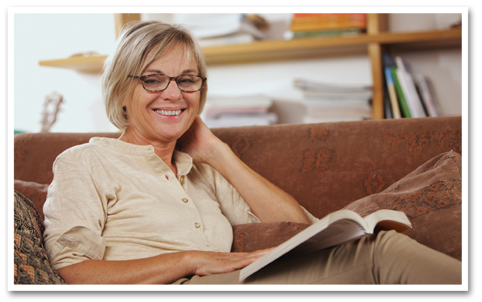 Smiling older woman on couch reading